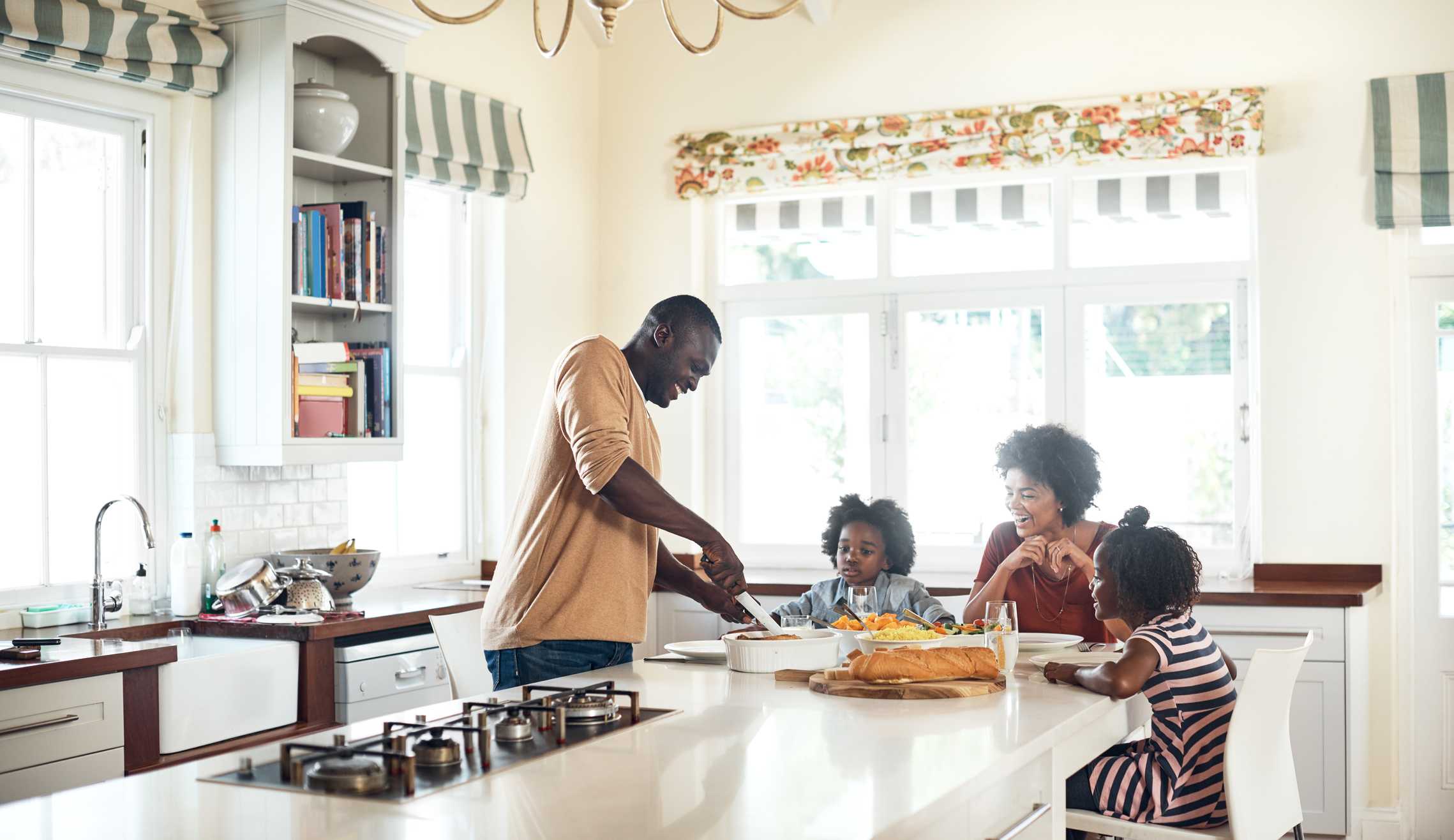 Evaporative humidifier installation and family enjoying time in a bright kitchen, emphasizing indoor air quality in Phenix City, AL.