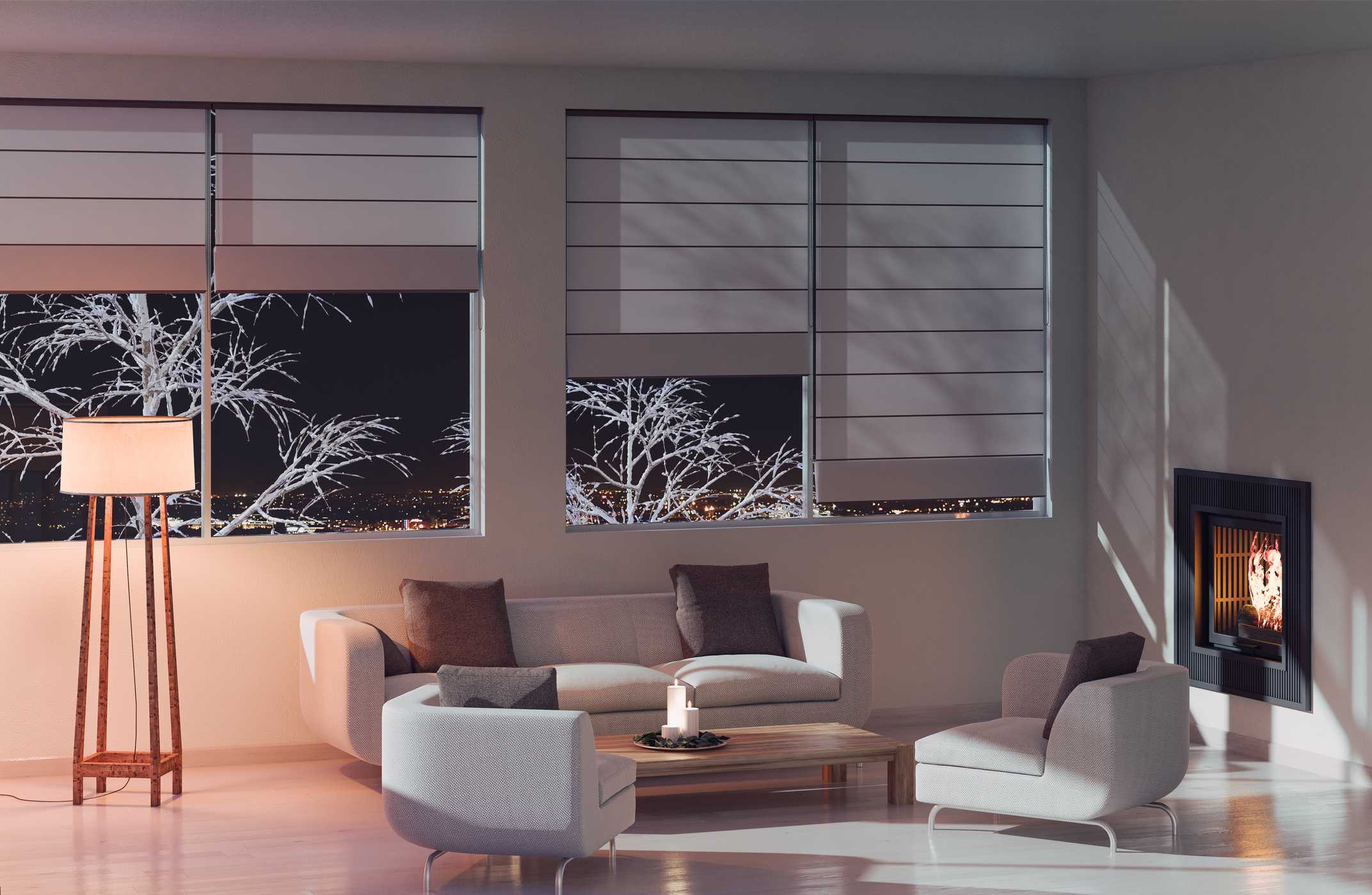 Cozy living room with modern furniture, large windows showing snowy trees, warm lighting from a floor lamp, and a fireplace, emphasizing comfort and heating needs in Phenix City, AL.