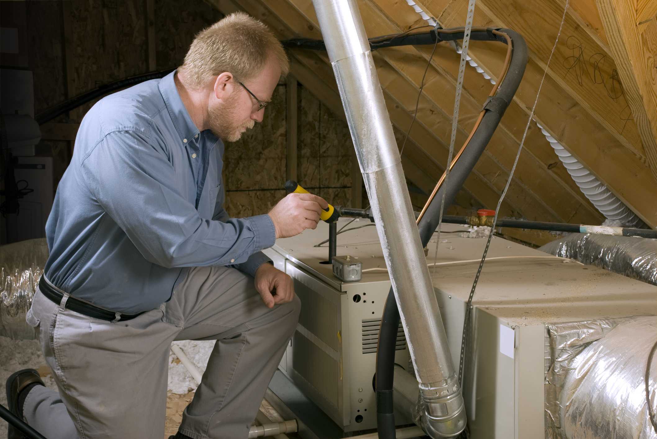 Technician inspecting ventilation system in attic, emphasizing indoor air quality services in Phenix City, AL.