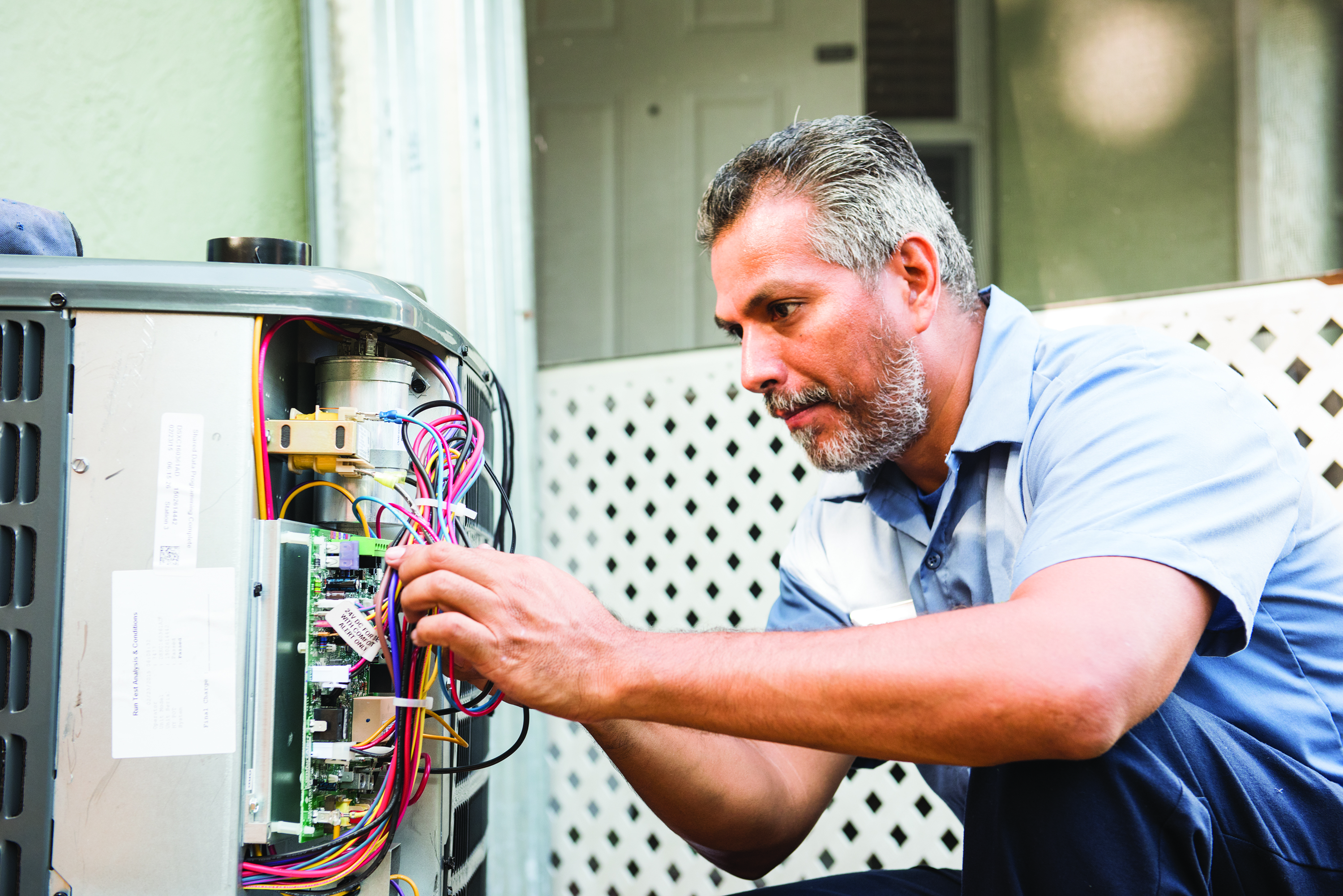 HVAC technician performing maintenance on air conditioning unit, focusing on electrical components and wiring, emphasizing professional AC maintenance services in Phenix City, AL.
