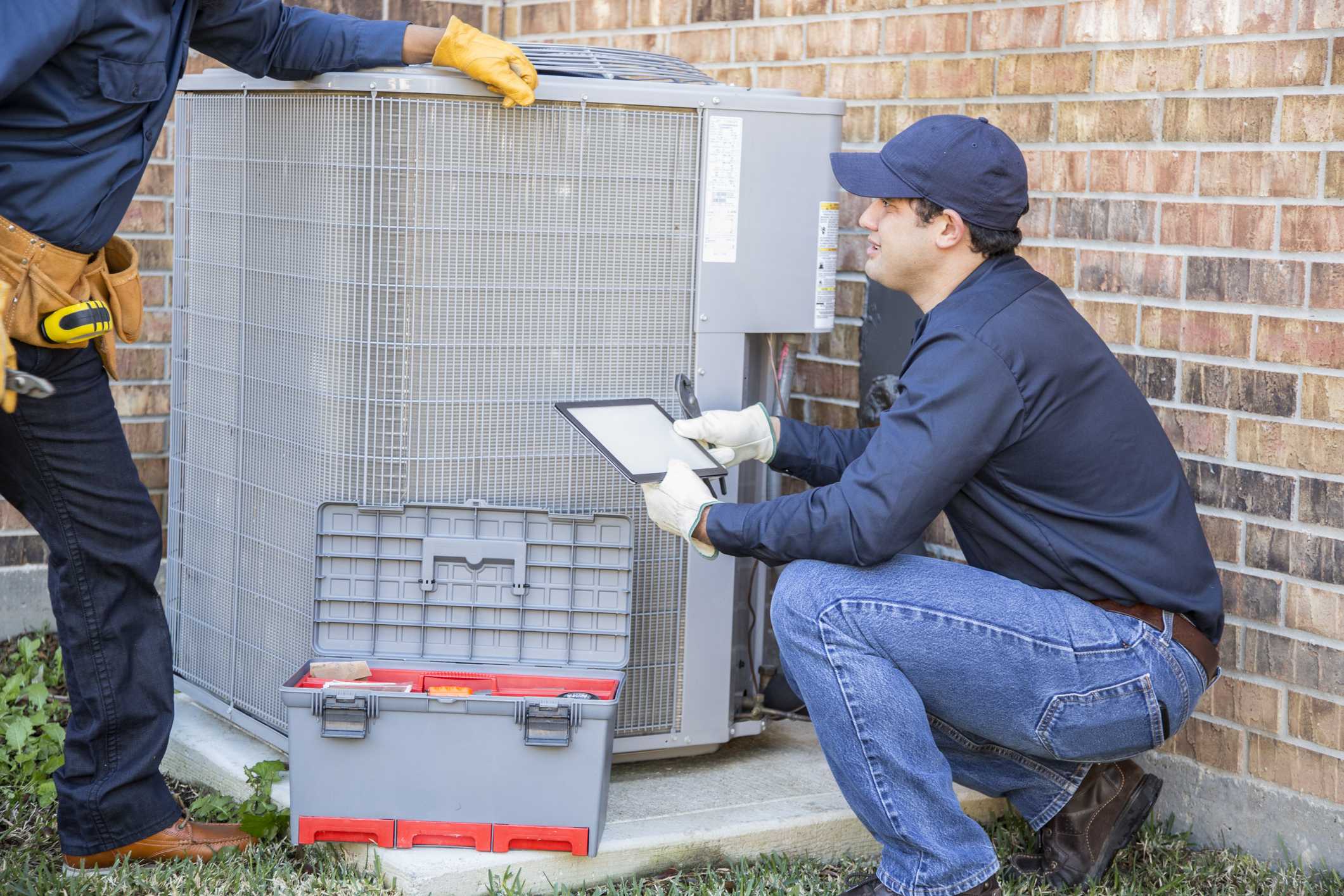 Technician inspecting air conditioning unit during AC replacement service in Phenix City, AL.