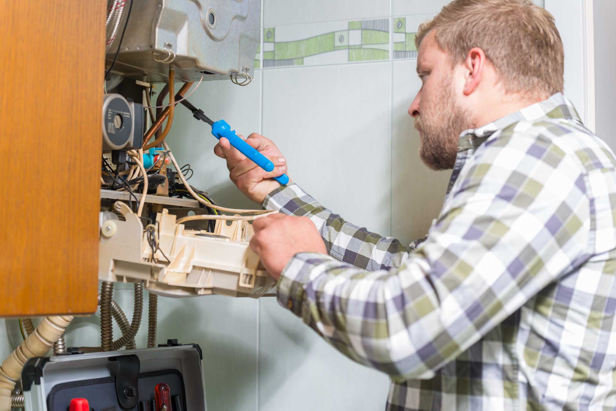 Technician performing heater maintenance with tools in residential setting, highlighting heater replacement services in Phenix City, AL.